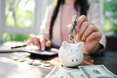 Closeup Of Business Woman Hand Putting Money Into Piggy Bank For